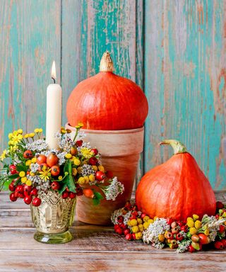 pumpkin display with candles and berries on a wooden table