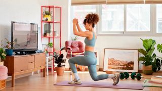 Woman performs the lunge exercise in front of a TV in a living room