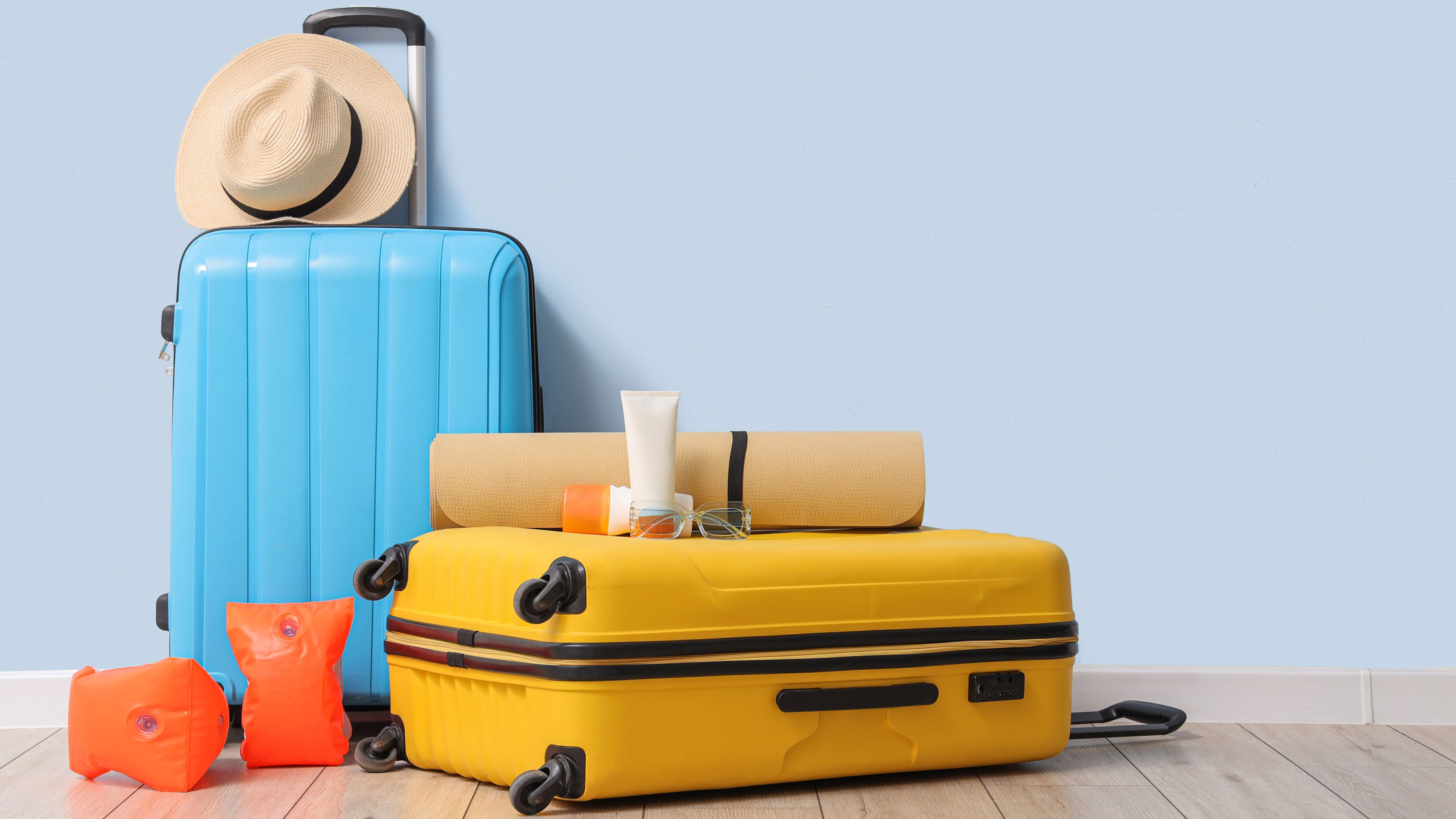 One small blue suitcase next to larger yellow suitcase on floor