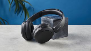 A photo of the Sony WH-CH520 wireless over ear headphones, resting on a stone surface against a black marble block and a blue background