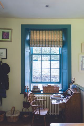 yellow home office with blue painted woodwork and window sill stripe window blind