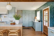 a light blue kitchen with wooden island