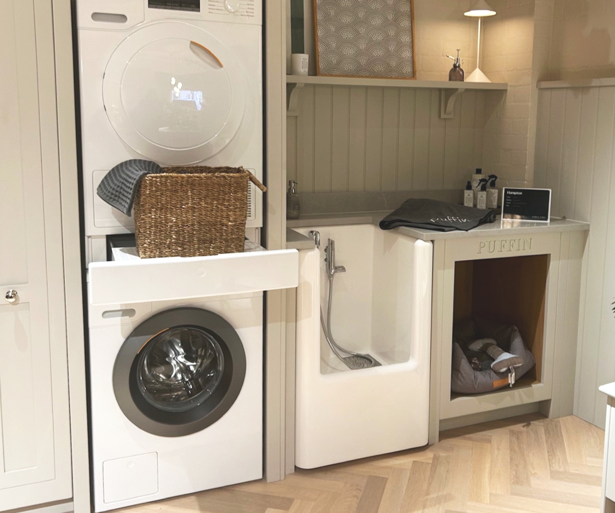 Incredible dog shower unit displayed in utility room with washer and dryer stacked next to it on one side and built in dog bed on other side