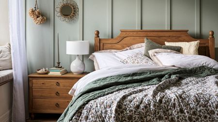 A blue panelled bedroom with a wooden bed and matching night stand. 