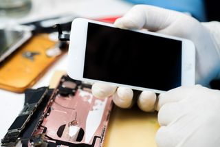 Rubber gloved hands disassembling an iPhone 