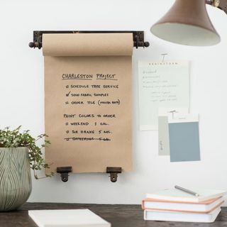 A roll of brown paper hanging on an antique looking wall roll. Two brass clips attached to the bottom