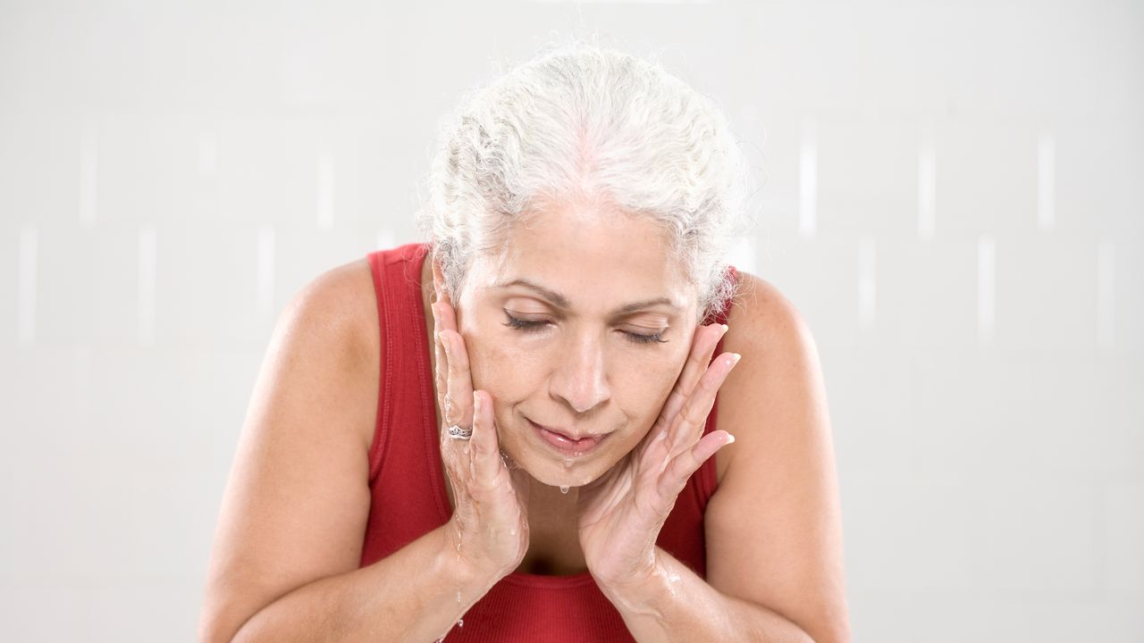 woman washing face over sink