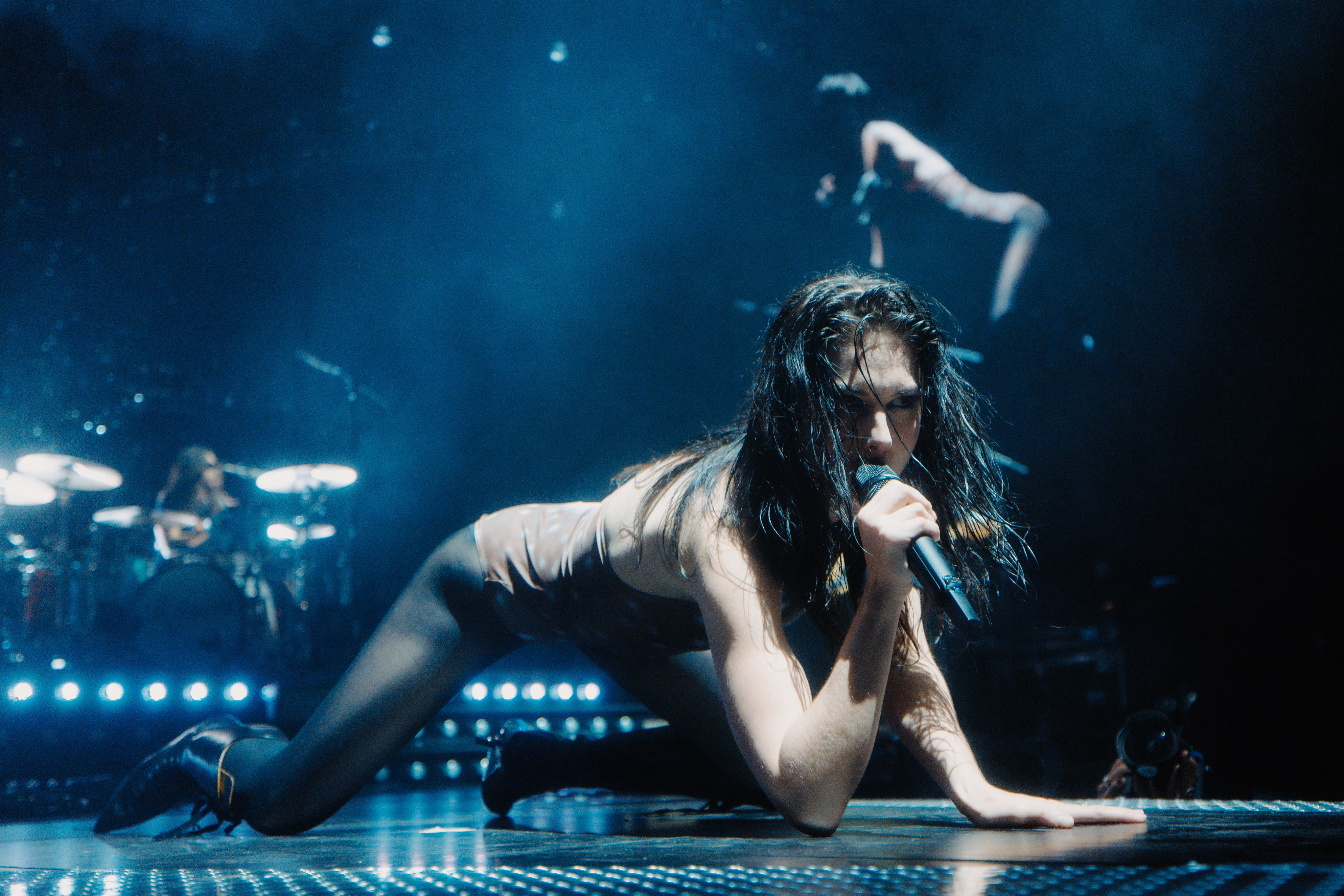 ellie rowsell of wolf alice performing on stage crawling on the ground and singing into a microphone