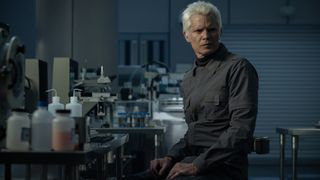 Kirsh sitting at a laboratory table and looking over his left shoulder in Alien: Earth