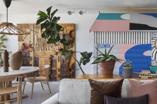 Icon Wood House by Henkin Shavit Design Studio features a round table with chairs and vases on, wall art and indoor plants.