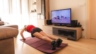 Woman doing push-ups in her front room, following a YouTube workout