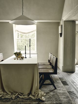 grey minimalist dining room with large line table cloth and brown chairs