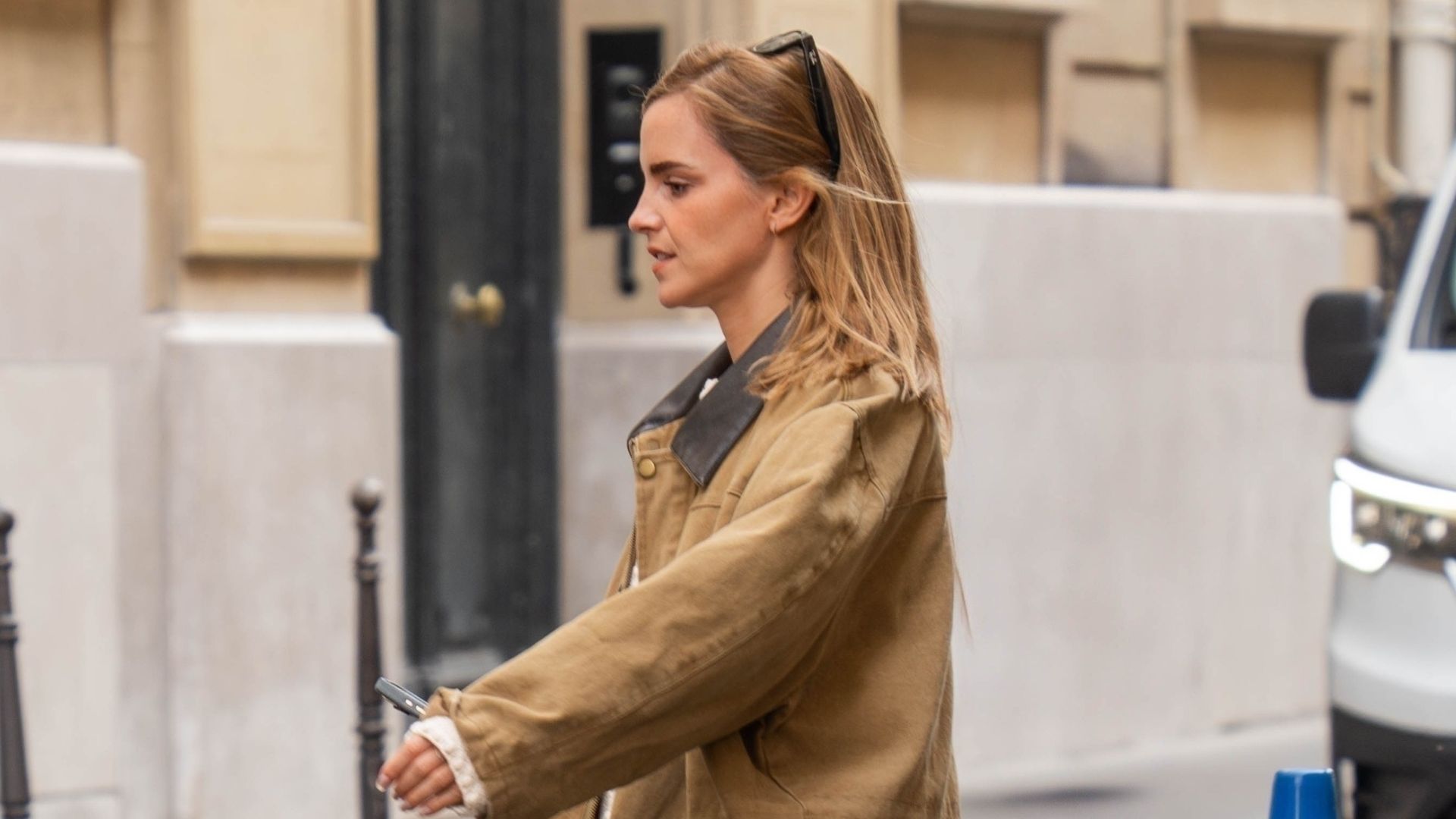 Emma Watson steps out in Paris wearing a barn jacket in a light brown shade with straight-leg jeans and Birkenstock mules.