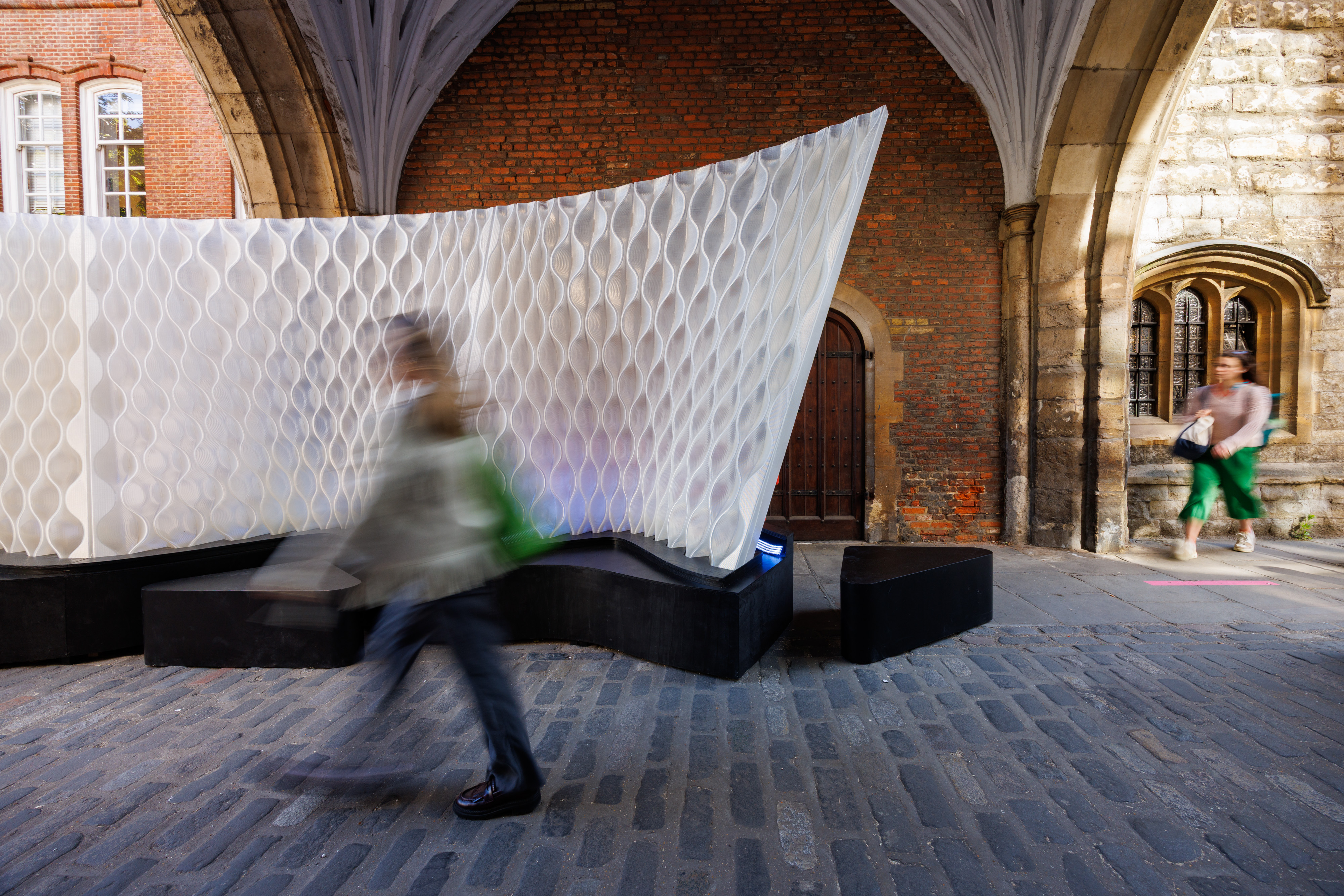 blurry figure walks past honeycomb wall structure