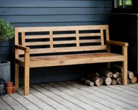 A modern wooden garden bench in front of a dark grey panelled wall