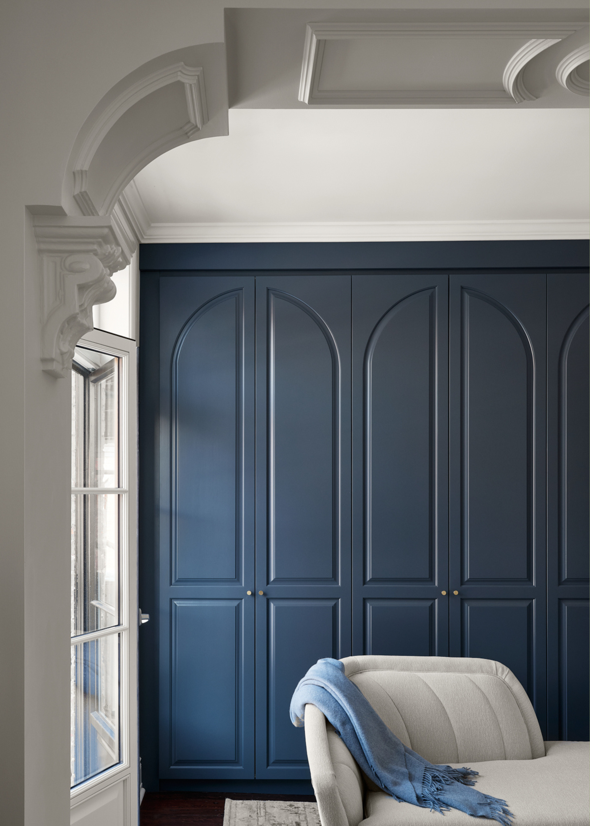 A bedroom with a blue wardrobe and a white fainting couch