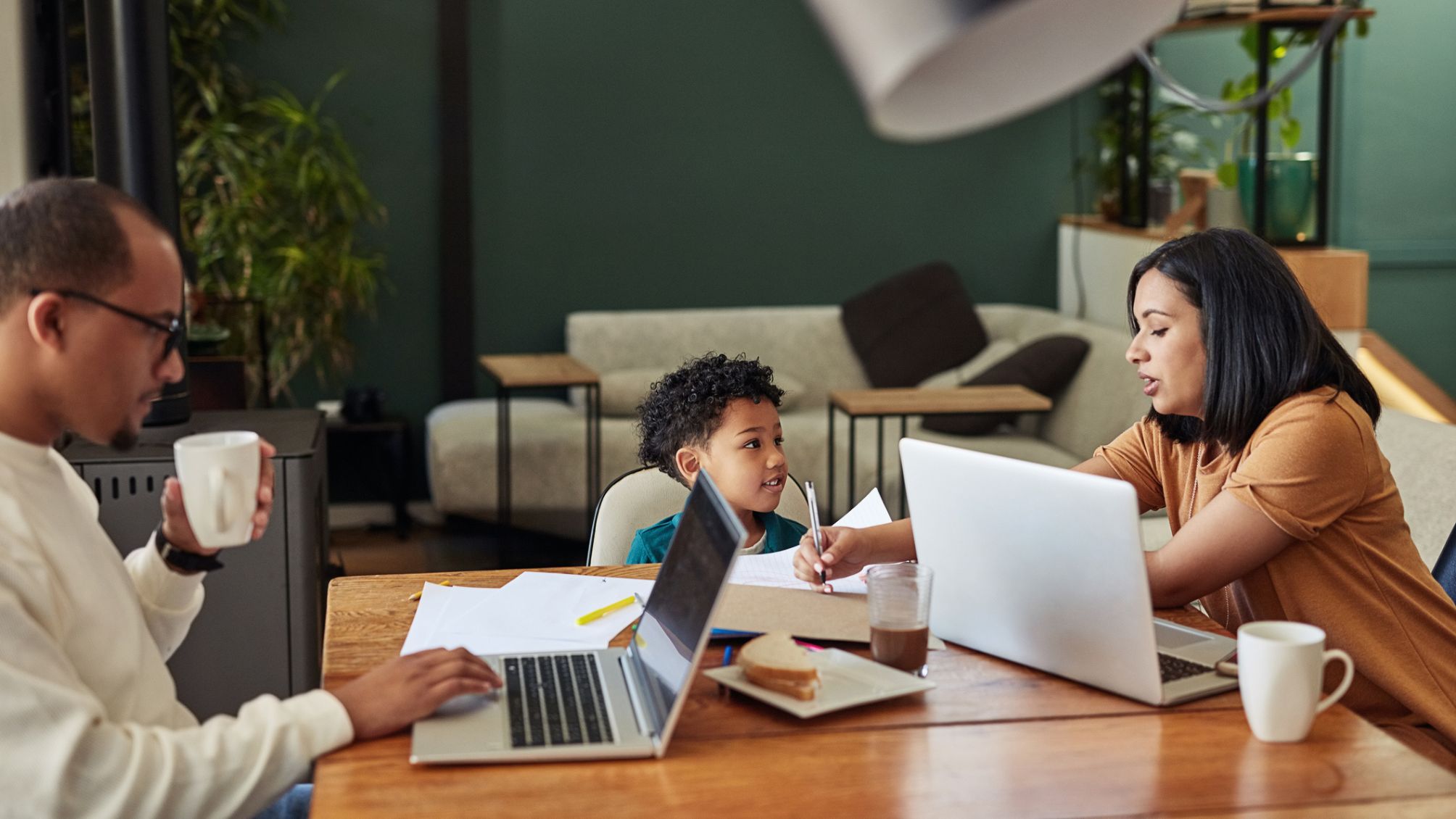 A family sitting at the dining room table working on laptops. 