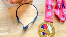 Shokz OpenRun Pro earphones next to writer Jessica's Adidas Manchester Marathon finisher medal