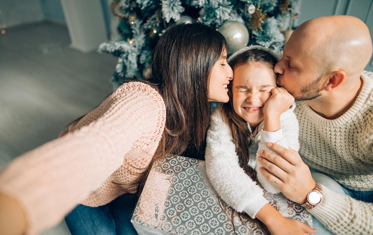 Mum and dad kissing their daughter on Christmas Day