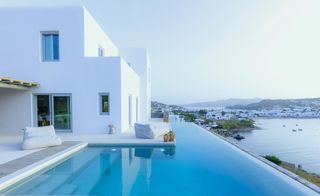 White exterior of the building with shaped, white beanbags at the side of the infinity pool