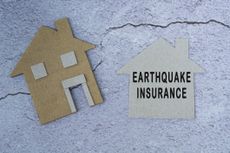 Earthquake insurance text on paper house model.