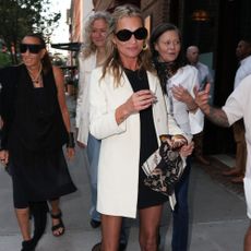 Kate Moss walks down the street in New York wearing a cream jacket with a LBD, black semi-sheer tights and black ballet flats.