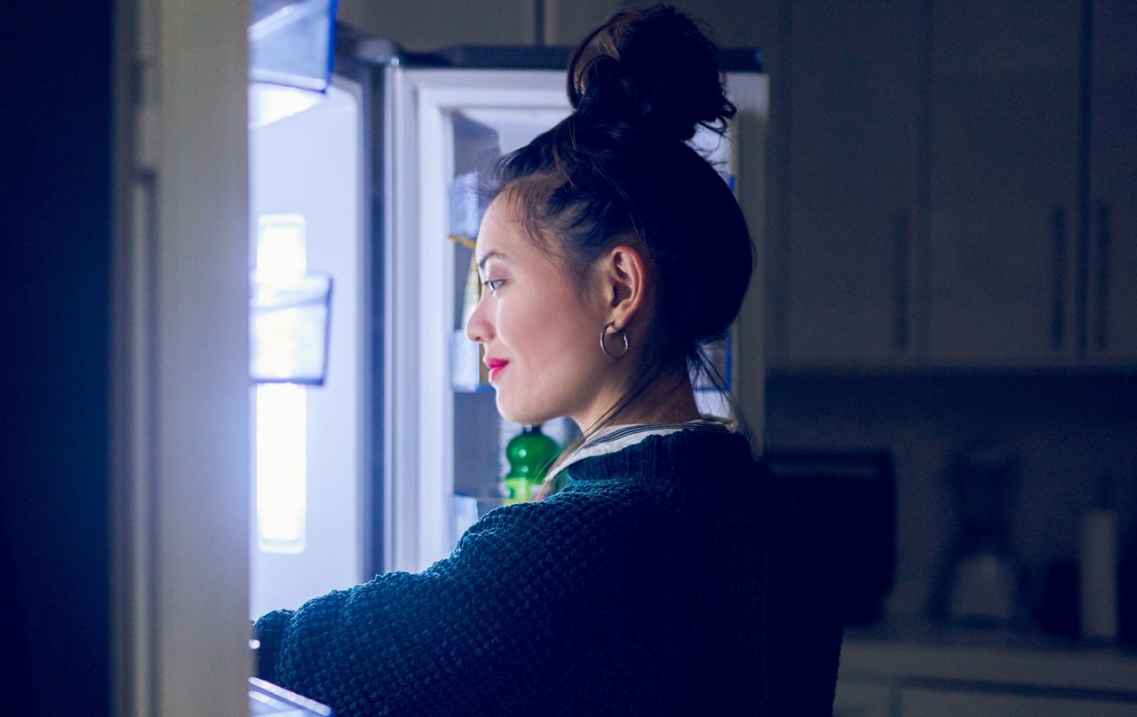 Young woman looking in the fridge for the best food to eat at night