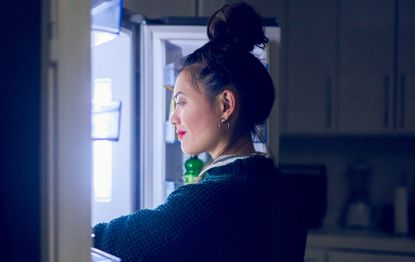 Young woman looking in the fridge for the best food to eat at night