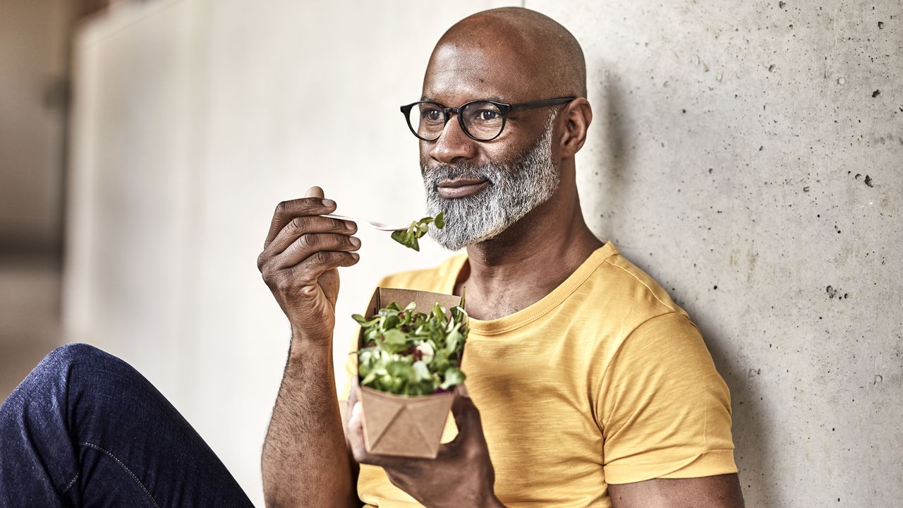 Man sitting down eating a salad mindfully