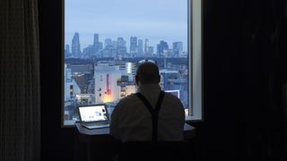 Man looking out of hotel window at Shinjuku business district