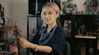 A woman sculpts a creature from clay