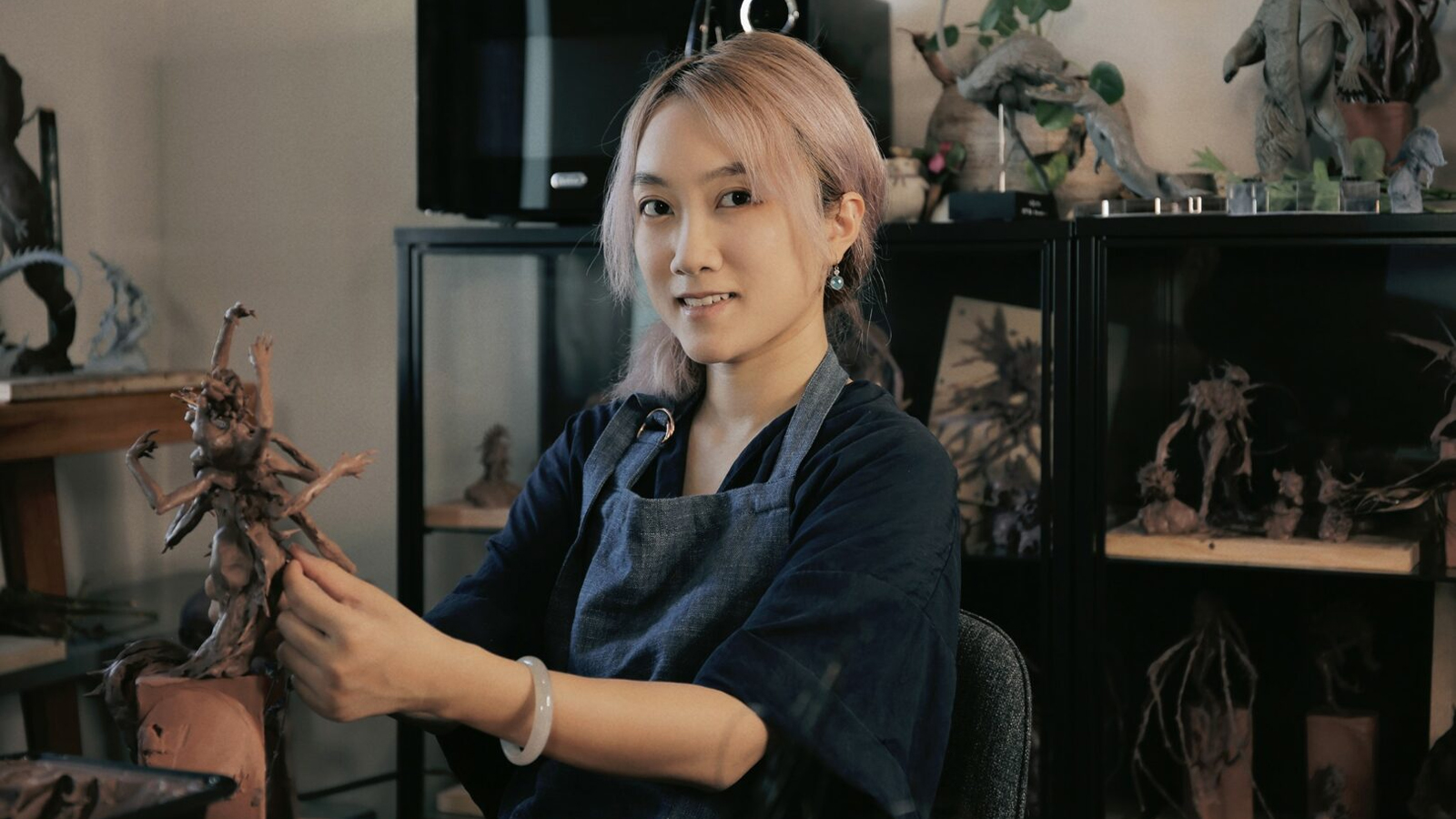 A woman sculpts a creature from clay