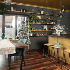 Black kitchen with gold island, bi-fold doors and dining table and Christmas tree