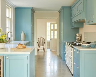 Modern country style light blue galley kitchen with white aga and stone flooring
