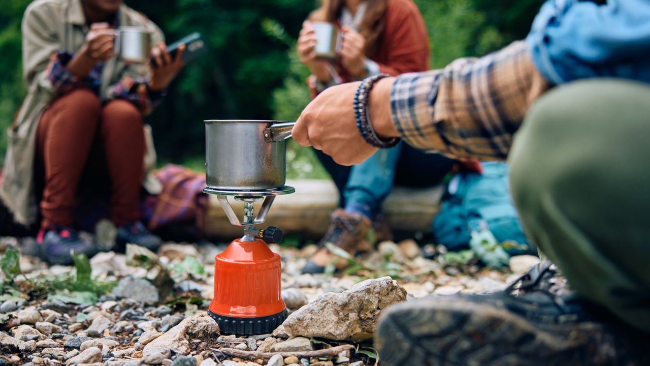 A group of campers boiling water on a camping stove