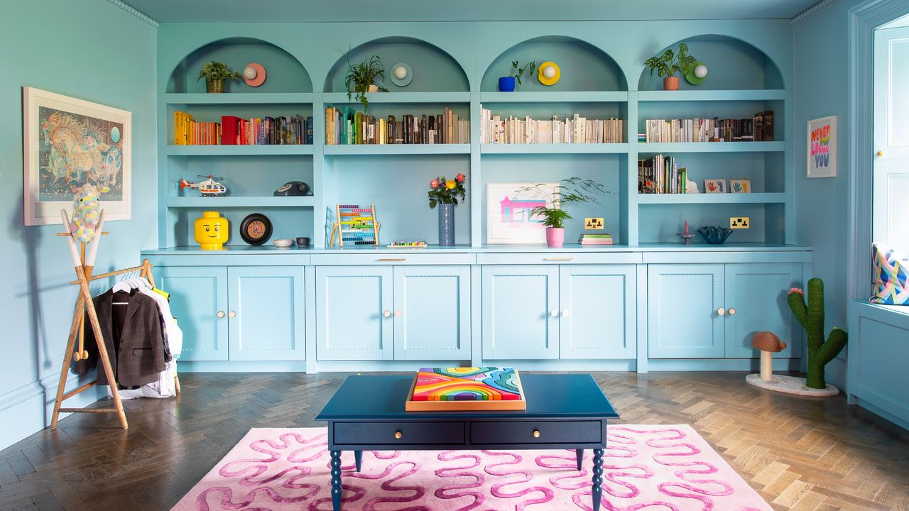 A colour-drenched room in bright blue with a built-in library with arches