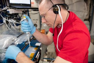 Expedition 56 Commander Drew Feustel fills protein crystal growth (PCG) wells for a recent PCG experiment on the space station.