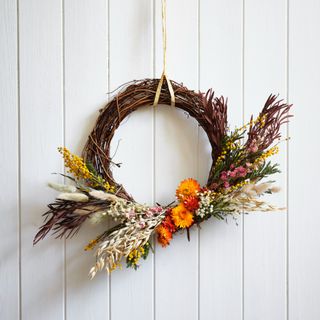 A dried-flower wreath hanging on a panelled white wall