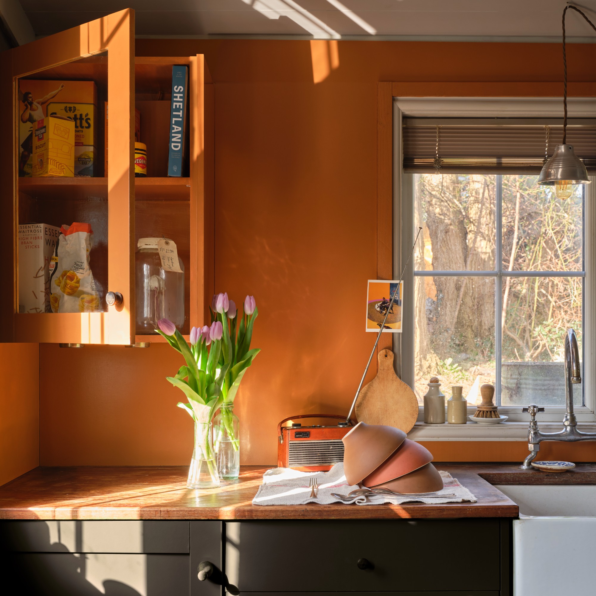 A kitchen painted in Farrow &amp; Ball&#039;s Marmelo shade on the walls and top cabinet and charcoal black on the bottom cabinets