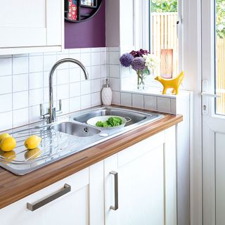 kitchen with white tiles butler sink and wooden worktop