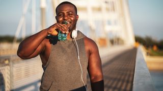 How to lose belly fat: Pictured here, young cheerful african-american man in sports clothing who is drinking water after exercise. He is exercising to reduce his body weight