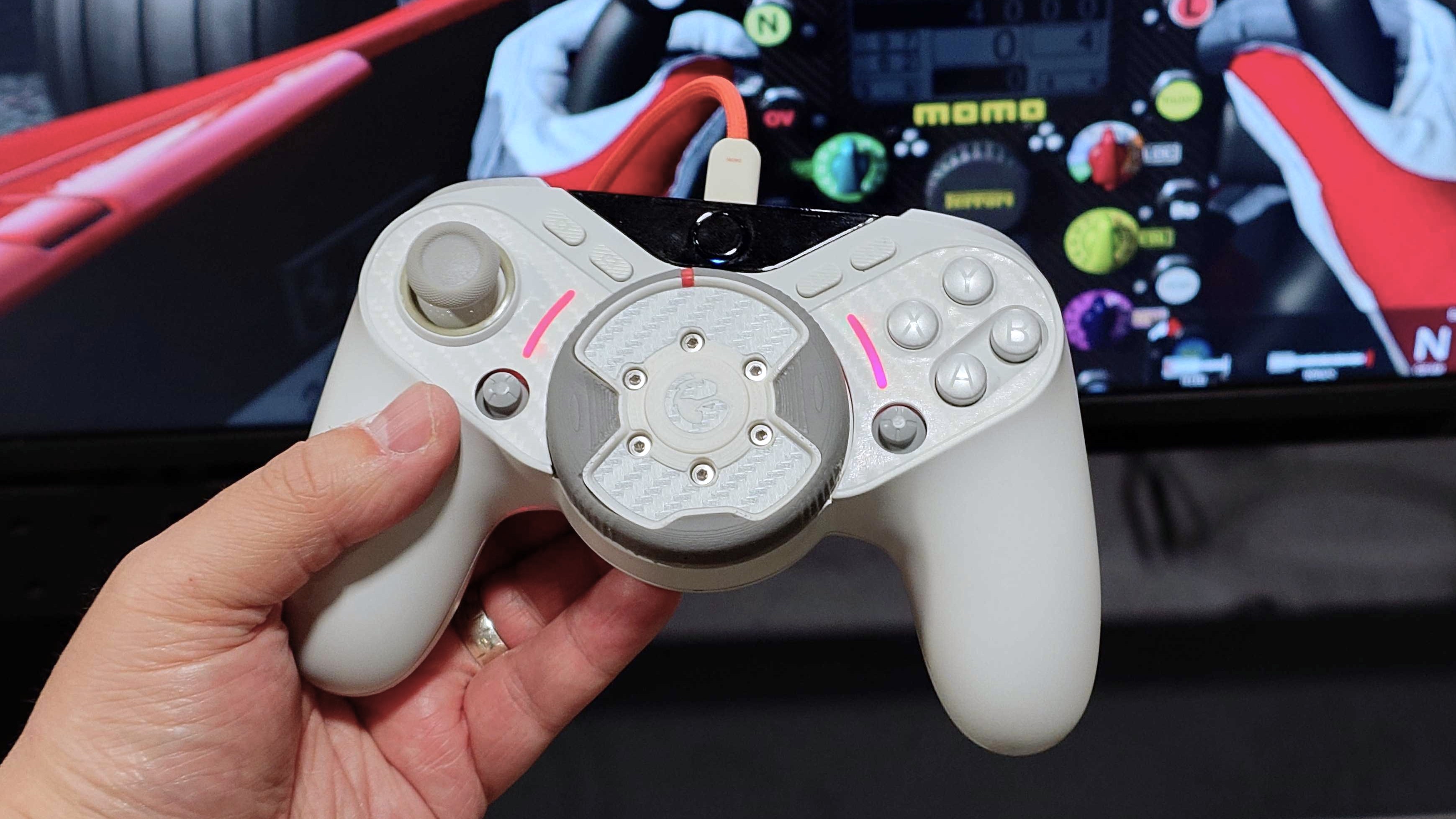 A prototype of the GameSir TR640 game controller in white with Assetto Corsa in the background. 