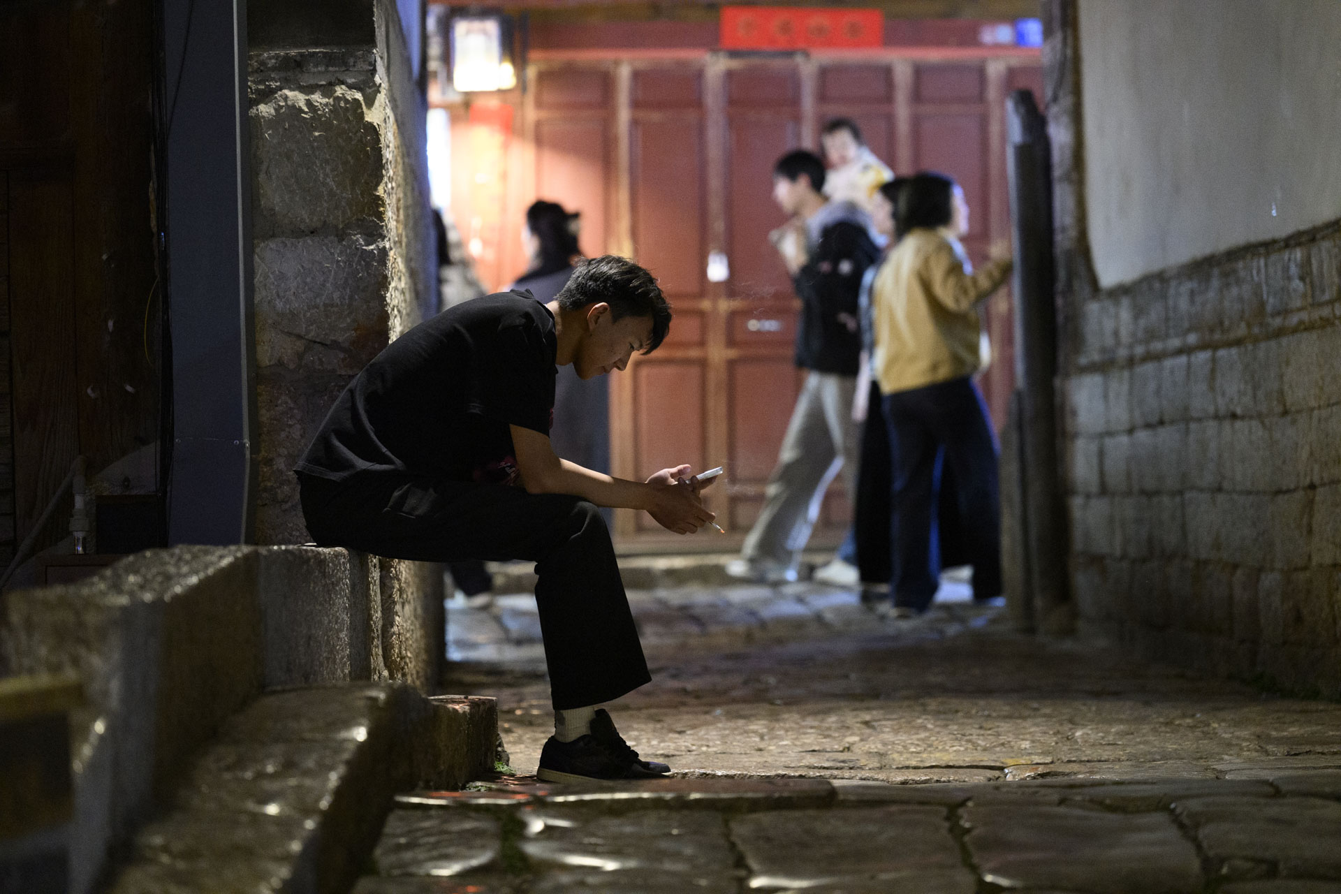 Nikon Z 70-200mm f/2.8 VR S II image gallery: a street scene at night in the Yunnan province of China - worker taking a cigarette break