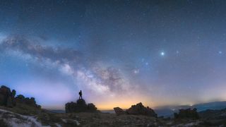 A man standing looking at a beautiful night sky including the Milky Way