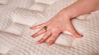 Our lead tester Alison places her hand on top of the Helix midnight elite mattress cover, which is cool to the touch but very slippery