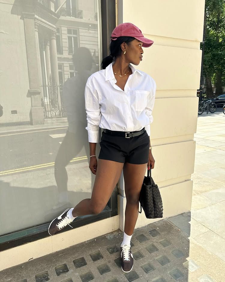 @nlmarilyn wears a pair of brown Nike trainers with black micro shorts and a white shirt
