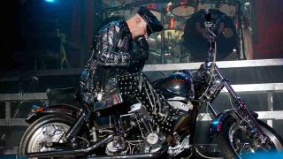 Judas Priest’s Rob Halford sitting on a motorcycle onstage in 2004