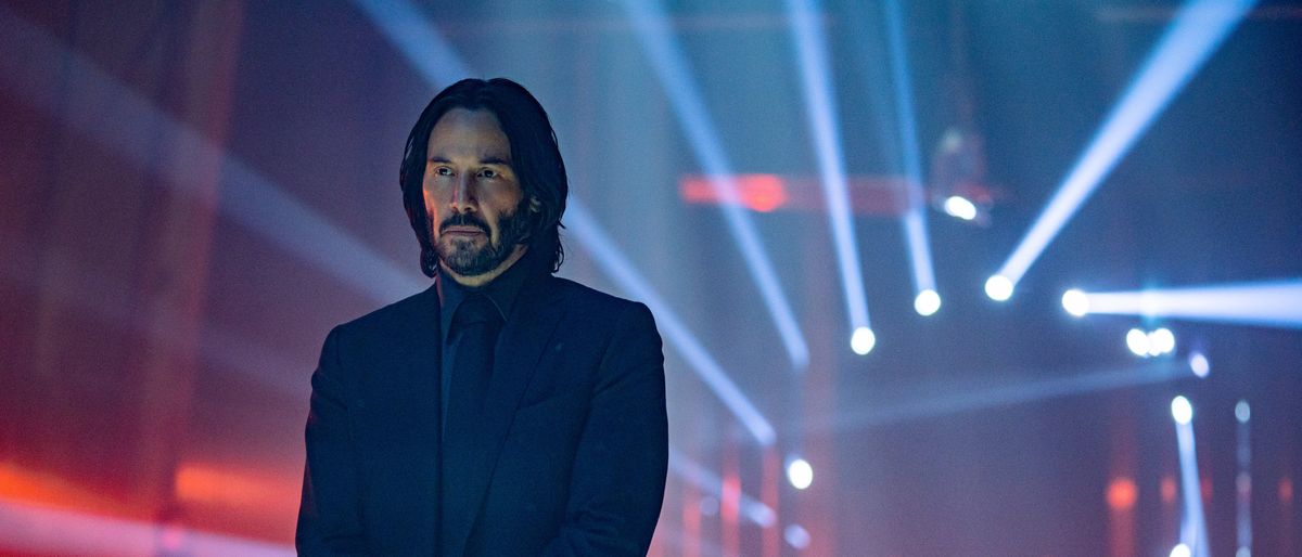 Keanu Reeves as John Wick, with spotlights behind him, in John Wick: Chapter 4