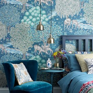 bedroom with blue arm chair and wallpaper wall and bedside table