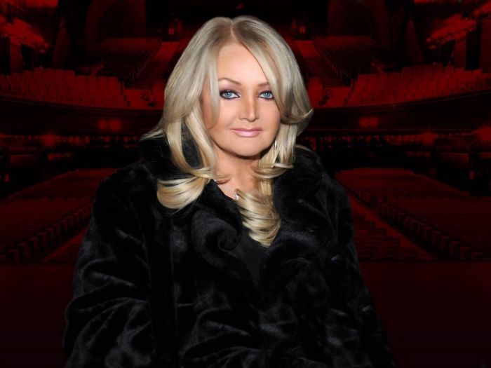 Bonnie Tyler in front of a darkened red theater backdrop